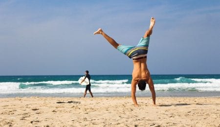 man doing handstand on beach